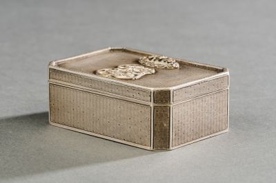 une petite boîte en argent posée sur une surface grise