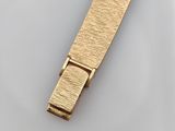 a close up of a gold tie bar on a white surface