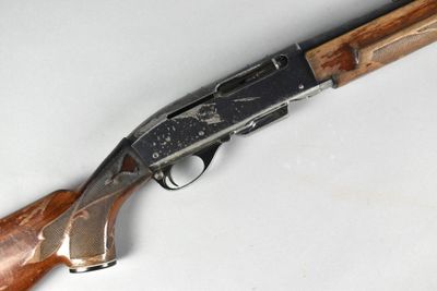 a close up of a rifle with a wooden handle on a white surface