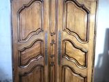a wooden armoire in a room with a white wall