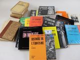 Plusieurs livres sont empilés sur une table devant un fond blanc.
