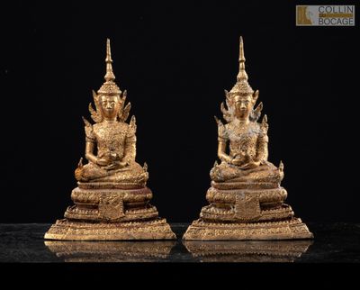 deux statues en or représentant des bouddhas assis sur un socle noir