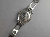 a close up of a watch on a table with a gray background