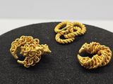 trois bijoux de couleur dorée posés sur une surface noire