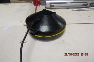 un objet noir posé sur une table, muni d'une poignée rouge