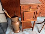 a wooden cabinet and a metal vase next to a wall