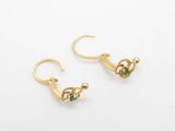 a pair of gold earrings with emerald stones