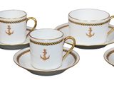 four coffee cups and saucers with gold trims on a white surface