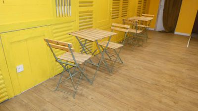 several chairs and tables in a room with yellow walls and wooden floors