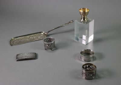 a bottle of perfume, a spoon, and other silver objects on a table