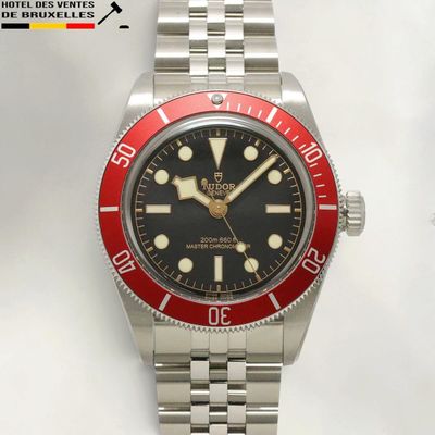 a red and black watch on a silver bracelet