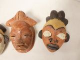 three african masks on a white surface with a white background