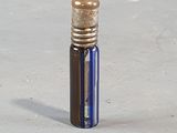 a small blue bottle with a gold cap sitting on a white surface