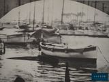 black and white photo of a man standing in front of a harbor filled with boats