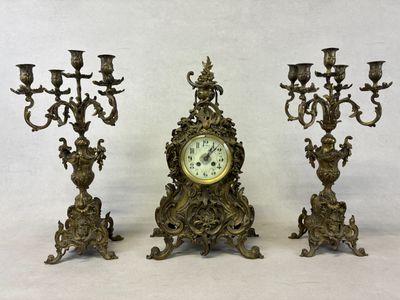 trois bougies et une horloge posées sur une table