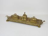 an old brass plate with two candles on it on a white surface