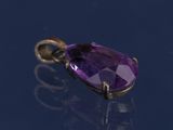 un gros plan d'un pendentif en pierre précieuse violette posé sur une surface bleue