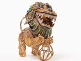 a gold and green lion with a cart on it ' s back