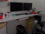 a desk with two monitors and a chair in the corner