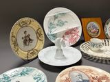 many plates with pictures of people on them on a table