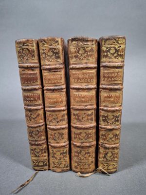 quatre vieux livres sont empilés les uns sur les autres sur une surface grise