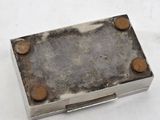 an old silver box with rust on it sitting on a white surface