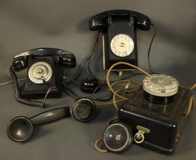 several old fashioned telephones are sitting on a gray surface