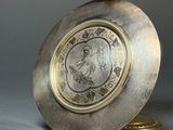 a silver and gold clock with a picture of a woman on it