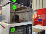 trois micro-ondes empilés les uns sur les autres dans un entrepôt