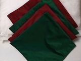 four pieces of red, green, and white napkins on a bed