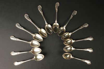 six cuillères en argent disposées en cercle sur une surface noire