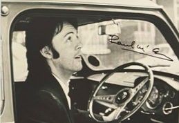 photographie en noir et blanc d'un homme assis dans une voiture, la main sur le volant