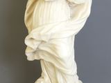 statue en marbre représentant une femme tenant un enfant dans ses bras, posée sur un socle en marbre