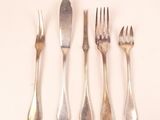 four forks and a knife on a white surface
