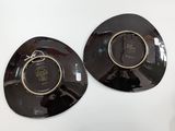 two black plates with gold rims are on a white surface