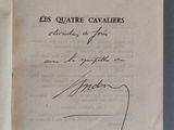 un livre ouvert, dont une page est recouverte d'une écriture manuscrite, posé sur une table