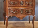 a small wooden chest of drawers on a wooden floor