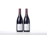 two bottles of red wine sitting on top of a white table