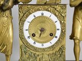 a gold clock that has a statue of a man and a woman on top of it