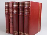 trois livres rouges superposés sur une surface blanche