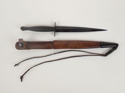 a close up of a knife on a white surface with a cord
