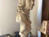 a bust of a man sitting on top of a table next to a lamp