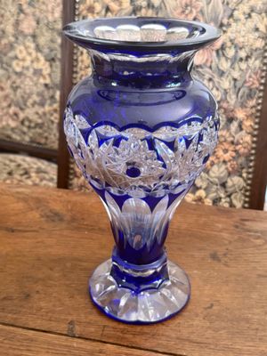 purple glass vase on wooden table in front of wallpapered wall