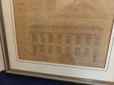 un vieux dessin représentant un bâtiment, encadré et posé sur un tapis bleu