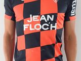 Cet homme porte un t-shirt rouge et noir et un pantalon noir.