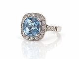 a close up of a ring with a blue topaz stone surrounded by diamonds