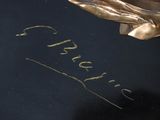 a gold statue of a bird with a name written on it