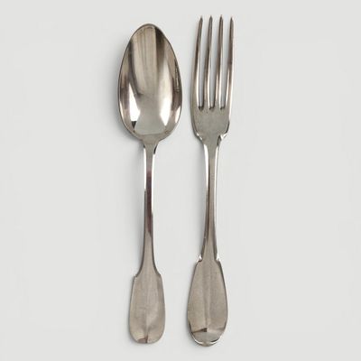 deux cuillères et une fourchette en argent sur une surface blanche