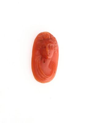 une image représentant un scarabée sculpté de couleur rouge, orné d'un visage de femme