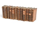 six vieux livres empilés sur une surface blanche